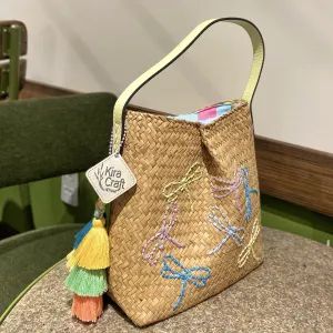 The Ribbon Lepironia Grass Bag adds a sweet touch to any rustic setting, featuring hand-embroidered details and serving as a unique sustainable fashion accessory, making it the perfect fashion gift for her