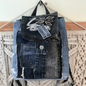 Sparkling mini backpack repurposed from old jeans creates signature piece for sustainable fashion enthusiasts, featuring unique drawstring design as distinctive fashion accessory and creative birthday gift.