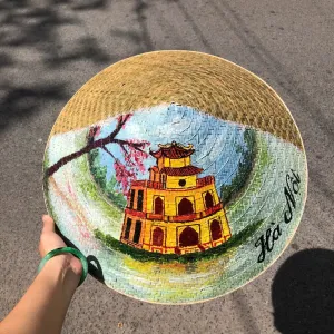 Nón lá cỏ bàng vẽ địa danh Việt Nam thủ công, kèm quai vải chắc chắn, là món quà lưu niệm mang đậm bản sắc Việt.