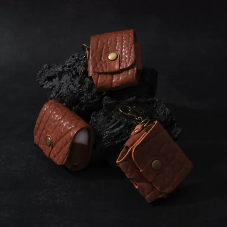 vachetta leather airpod case, natural leather material, protects earphones from scratches, includes brass keychain, elegant design
