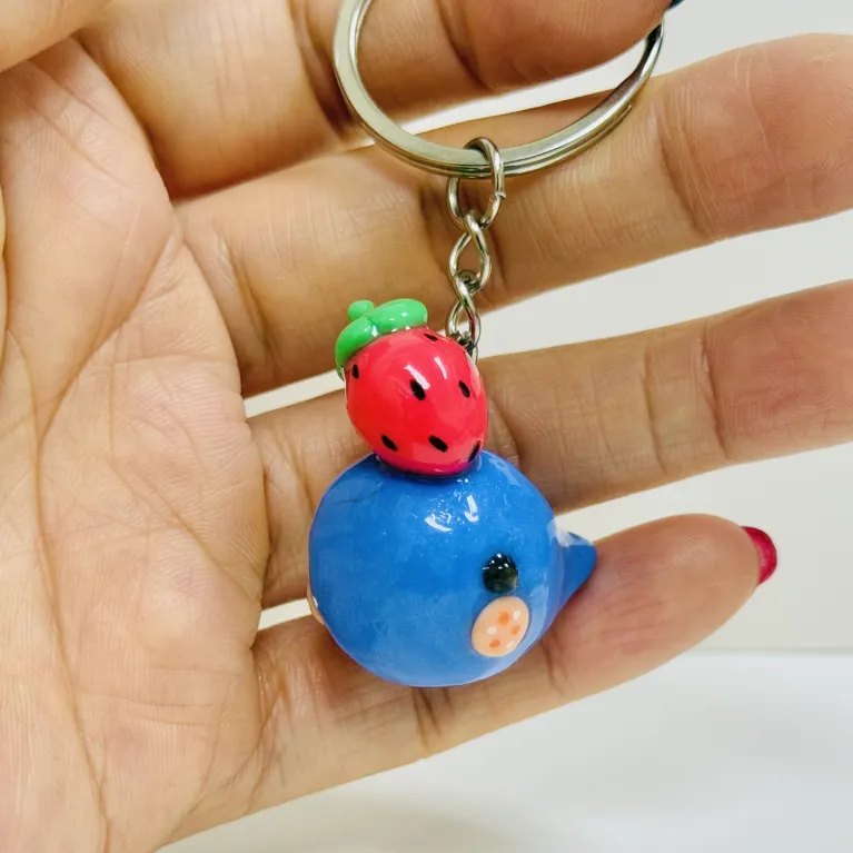 Melt with the cuteness of the Handmade Clay Strawberry-Hat Whale Keychain - an adorable handmade accessory that doubles as a unique bag charm and a thoughtful gift for her!