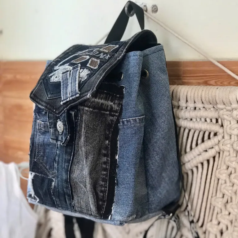 Sparkling mini backpack repurposed from old jeans creates signature piece for sustainable fashion enthusiasts, featuring unique drawstring design as distinctive fashion accessory and creative birthday gift.