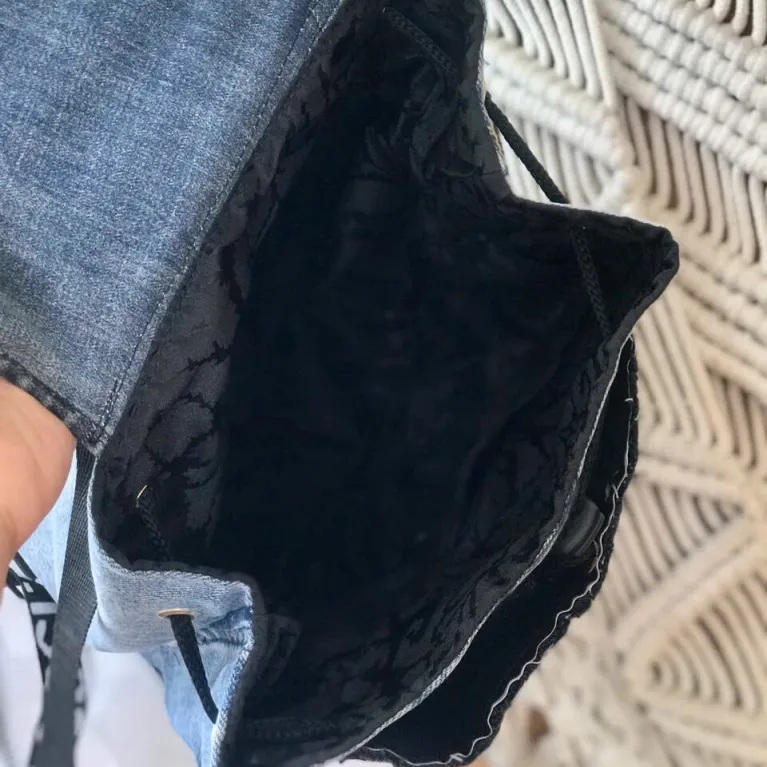 Sparkling mini backpack repurposed from old jeans creates signature piece for sustainable fashion enthusiasts, featuring unique drawstring design as distinctive fashion accessory and creative birthday gift.