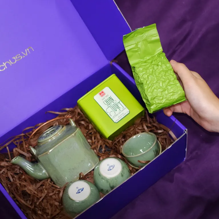 Tea set with Ancient Snow Shan Tea gift box showcasing premium Bat Trang ceramics and traditional tasting artistry, presented as an exclusive Vietnamese cultural souvenir with personalized card.