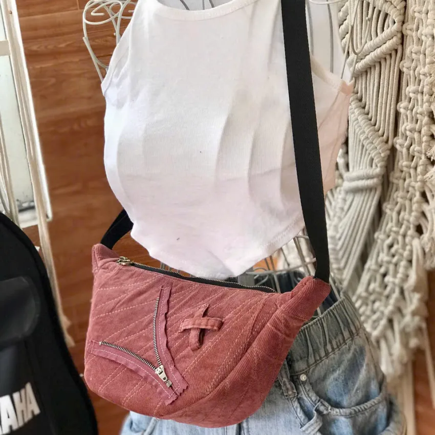 Pink half-moon crossbody bag from old jeans features one-of-a-kind color palette, creating a denim upcycled accessory and unique birthday gift for eco-conscious fashion lovers
